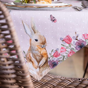 A pink tablecloth with an Easter bunny and colorful flowers on it