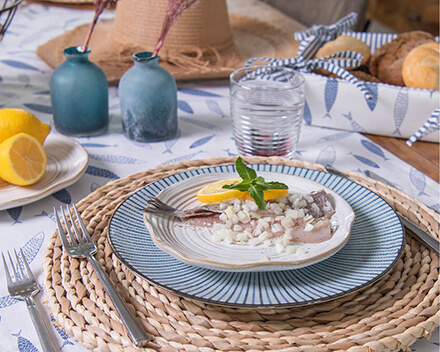 Tableware in lovely natural and blue tones, rattan placemats, and matching kitchen textiles with fish patterns