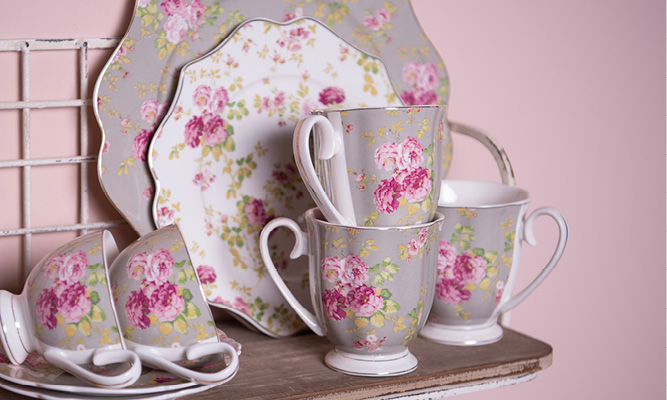 A country-style wall shelf with romantic tableware, including stacked mugs, dessert plate, breakfast plate, and teacups