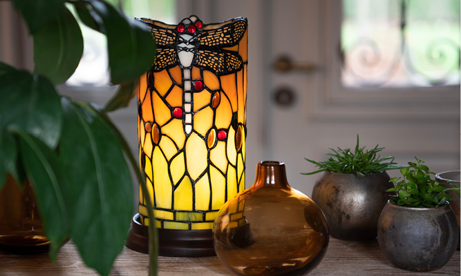 A classic Tiffany table lamp with dragonflies, next to it is a brown glass vase with two silver flower pots