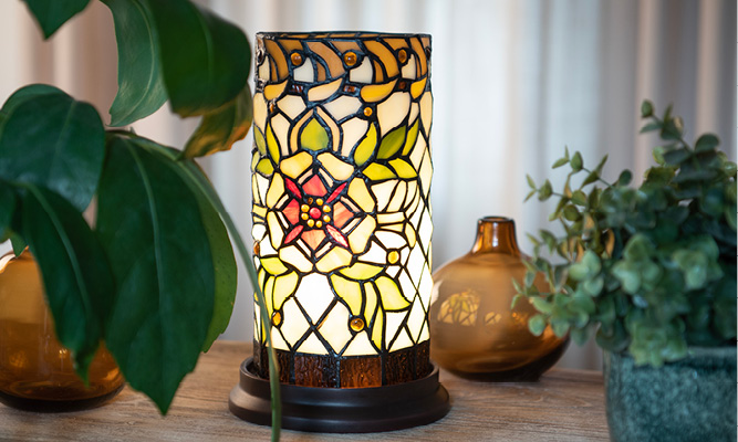 A round Tiffany table lamp with a botanical pattern featuring flowers and leaves