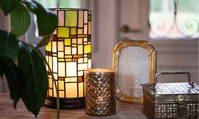Eine Tiffany-Tischlampe mit einem bunten Mosaikmuster und einem goldfarbenen Fotorahmen und Teelichthalter