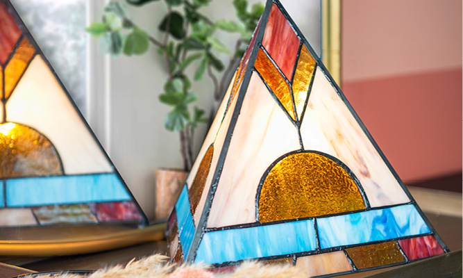 A Tiffany table lamp in the shape of a pyramid with vibrant colors such as pink, yellow, and blue