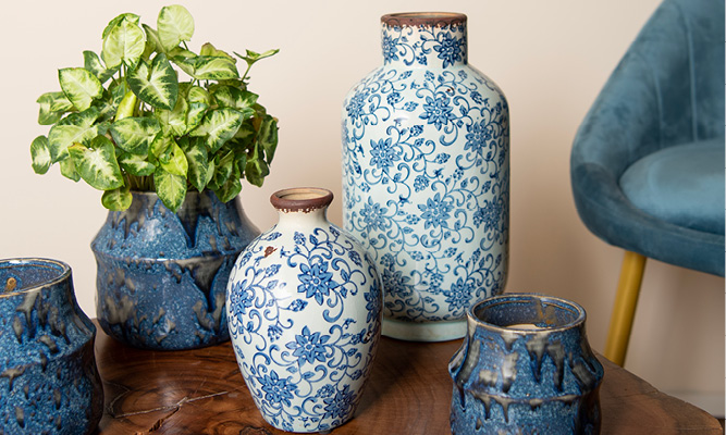 Une table basse en bois avec des pots de fleurs bleu foncé dessus et deux vases bleus de style campagnard