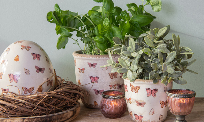 Butterfly flower pots with pink tealight holders and a wreath with a decorative egg inside