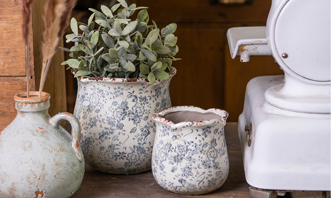 Twee brocante bloempotten met een grijs vaasje erbij waar droogbloemen in zitten