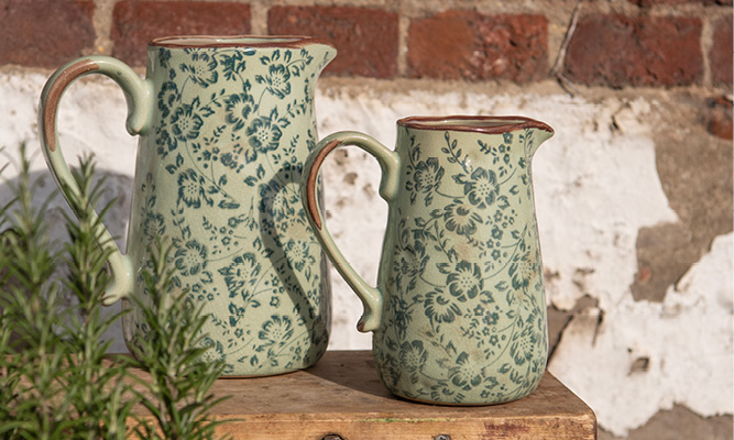 Two green decorative pitchers with green flowers