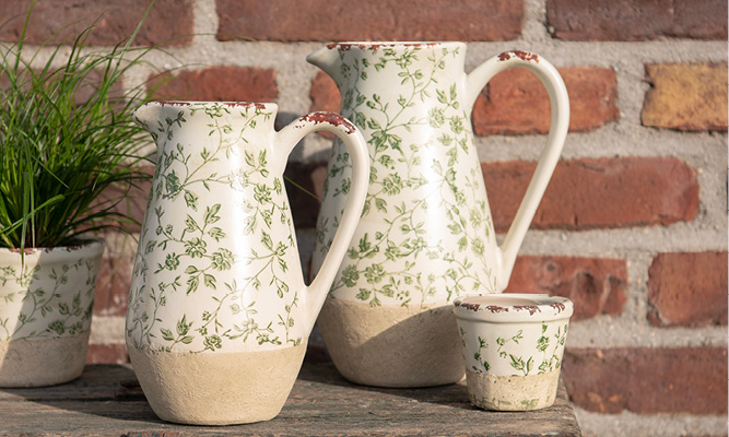 Two green pitchers and a flower pot with a pattern of branches and flowers