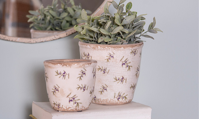 Twee bloempotten met een patroon van olijftakjes en een bloempot is gevuld met een kunstplantje