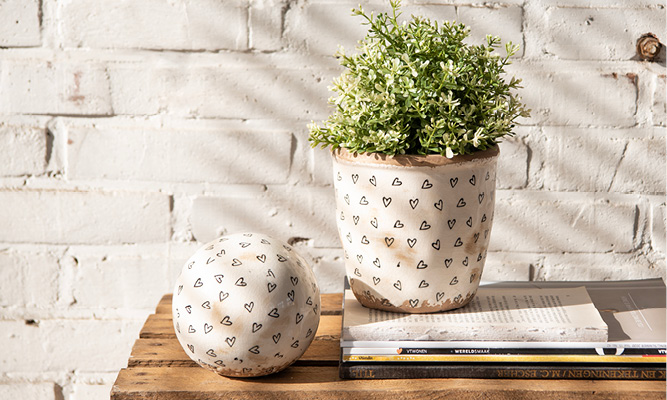 A modern flower pot with illustrated hearts and a decorative egg with black hearts