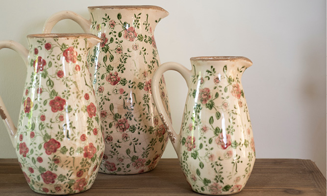 Three decorative pitchers with a country-style floral pattern featuring pink flowers and green leaves