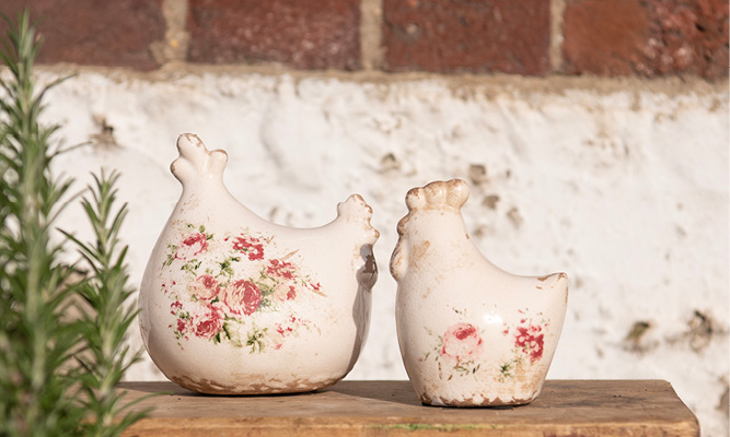 Two rustic chicken statues with old-fashioned peonies