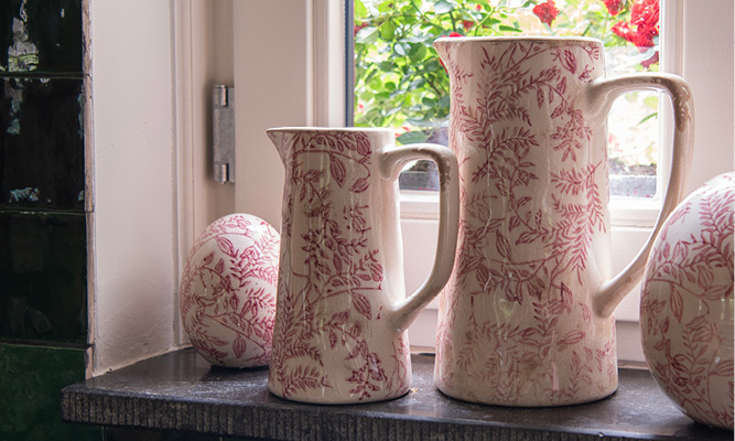Two decorative pitchers with a pink branch pattern and a decorative egg