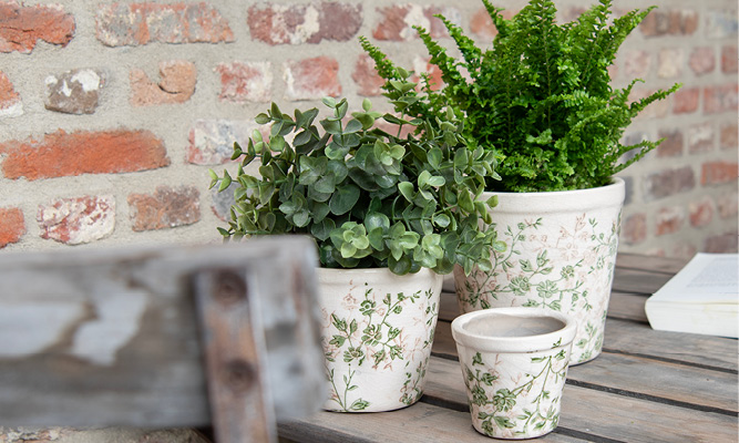 Trois pots de fleurs romantiques avec un motif floral et des plantes vertes