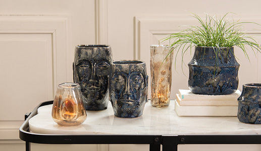 A marble table with two dark blue Easter Island flower pots and a dark blue flower pot with two brown glass vases