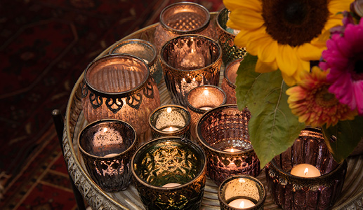 A tray filled with glass tea light holders in bohemian colors