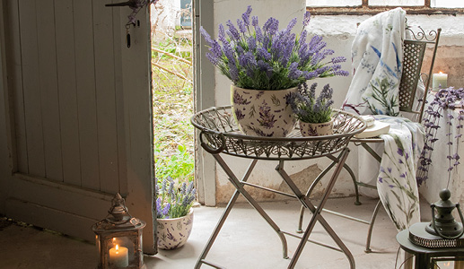 Ein romantischer Garten mit zwei Lavendelblumentöpfen und einem romantischen Eisenpflanzenhalter
