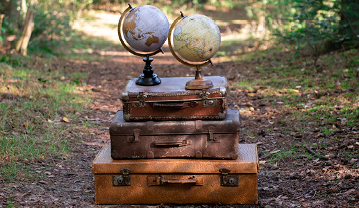 Trois valises anciennes empilées avec deux globes terrestres dessus