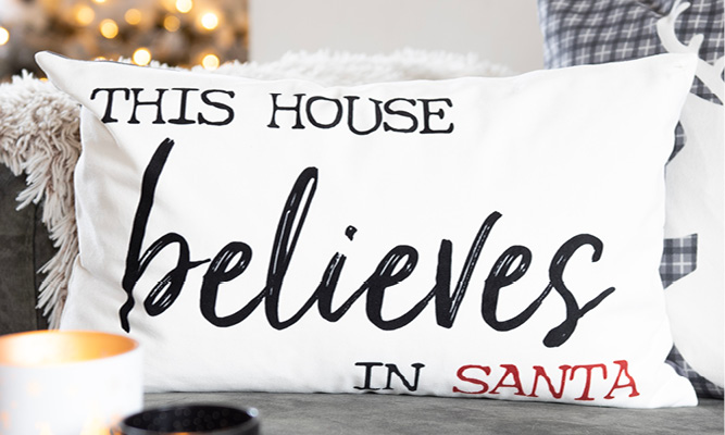 Un coussin rectangulaire blanc avec une citation de Noël dessus