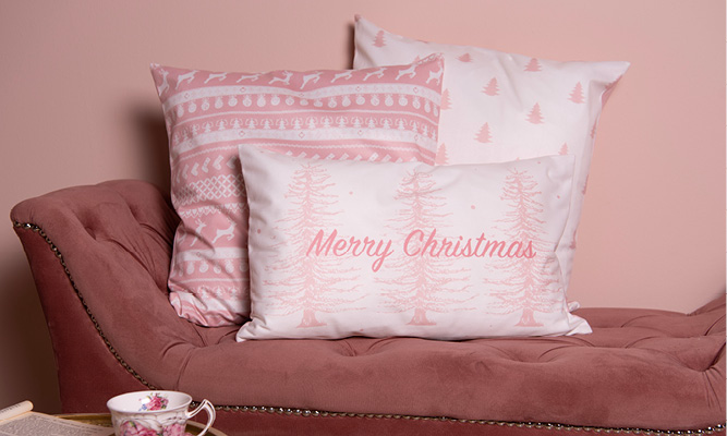 A pink bench with three pink romantic Christmas pillows